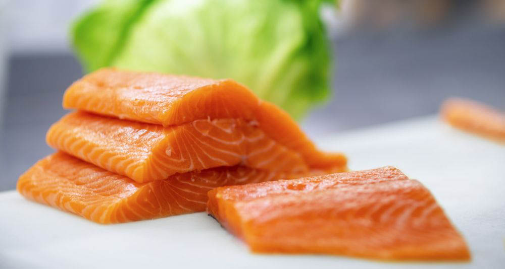 atlantic salmon filets on white counter with iceberg lettuce in the background